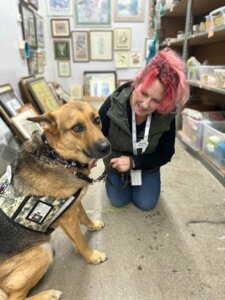 Kelly Ann and her service dog Dino, pose for a photo in the Bridging warehouse