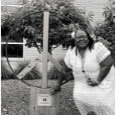 Woman standing by wooden statue of a peace symbol.