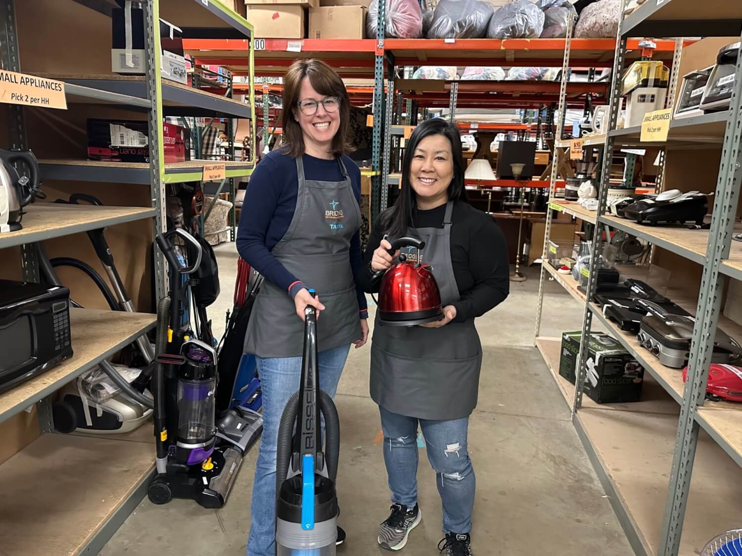 Volunteers posing with homewares in the warehouse.